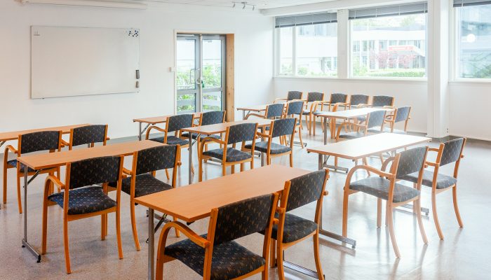 Et sett ed pulter og stoler som er vendtmot en tavle.